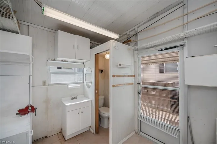 Bathroom with toilet, tile patterned floors, a healthy amount of sunlight, and vanity