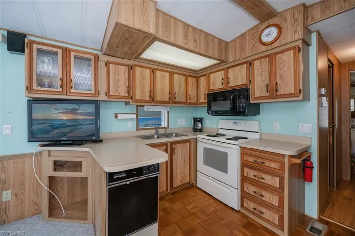 Kitchen with visible vents, a sink, light countertops, black appliances, and glass insert cabinets