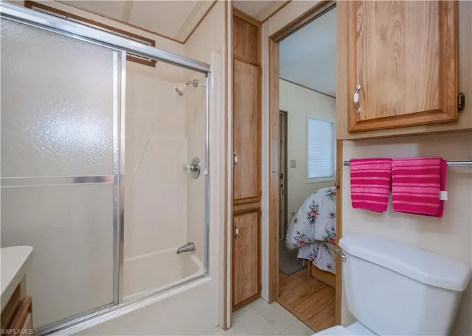 Full bath with toilet, tile patterned flooring, and bath / shower combo with glass door