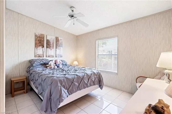 Bedroom with wallpapered walls, tile patterned flooring, a textured ceiling, and a ceiling fan