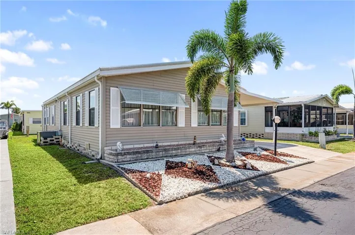 Manufactured / mobile home featuring a sunroom, an attached carport, and a front lawn