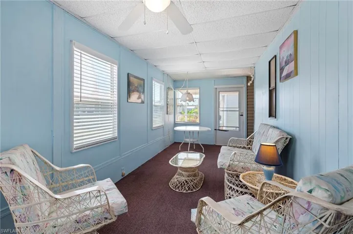 Living area with ceiling fan, a drop ceiling, and carpet flooring