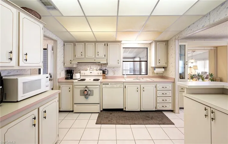Kitchen featuring light countertops, wallpapered walls, a sink, and white appliances