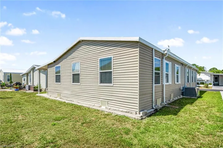 View of side of home with central AC unit and a lawn