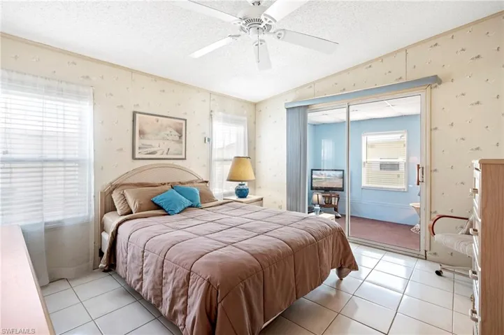 Bedroom featuring light tile patterned floors, multiple windows, a textured ceiling, and wallpapered walls