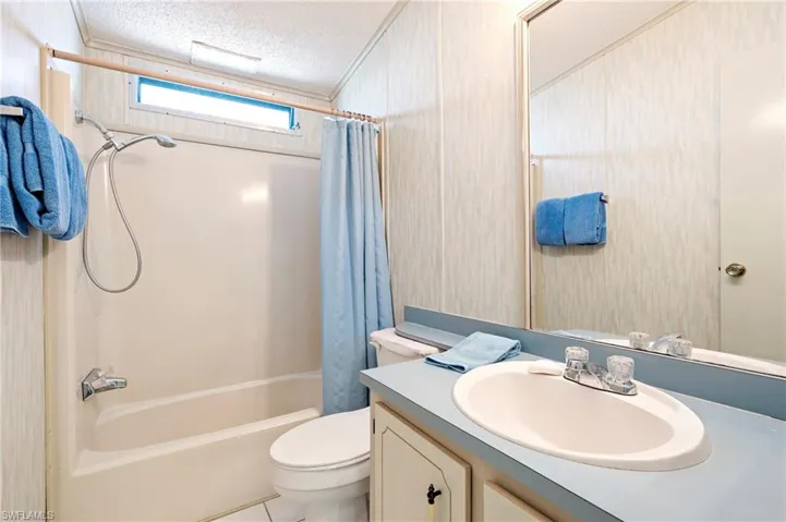 Full bathroom featuring vanity, tile patterned flooring, shower / bath combination with curtain, a textured ceiling, and toilet
