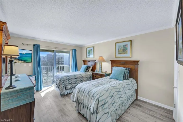 Bedroom featuring access to exterior, ornamental molding, light hardwood / wood-style floors, and a textured ceiling
