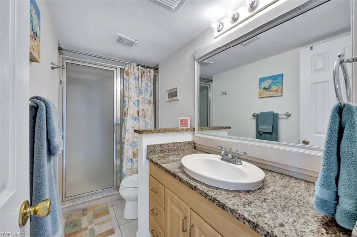Bathroom featuring vanity, a textured ceiling, tile patterned floors, toilet, and walk in shower
