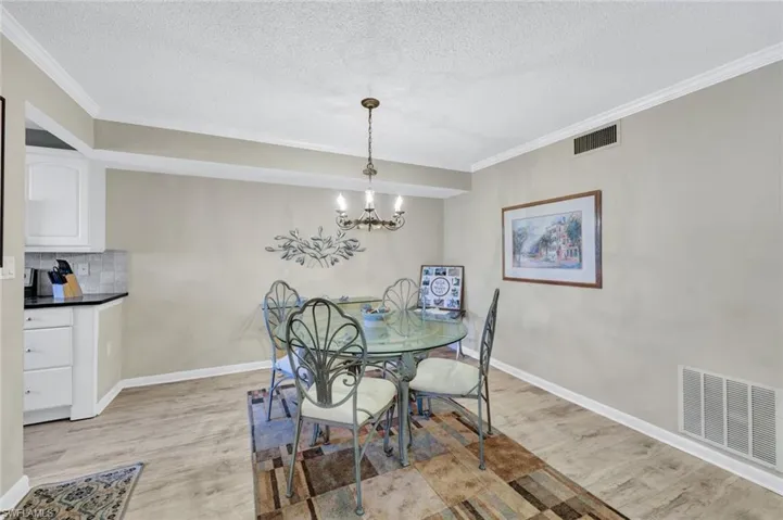 Dining area with a notable chandelier, light hardwood / wood-style flooring, and ornamental molding