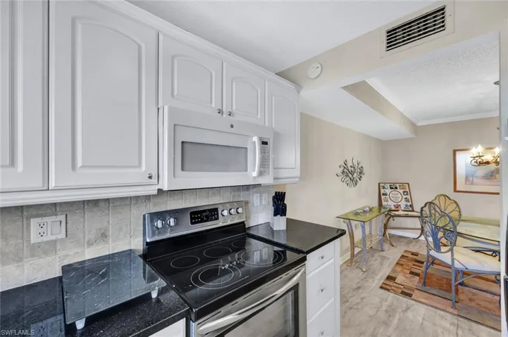 Kitchen featuring tasteful backsplash, white cabinets, light wood-type flooring, and stainless steel electric range
