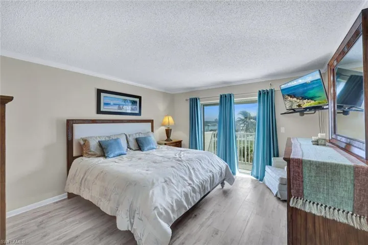 Bedroom with access to exterior, ornamental molding, a textured ceiling, and light wood-type flooring