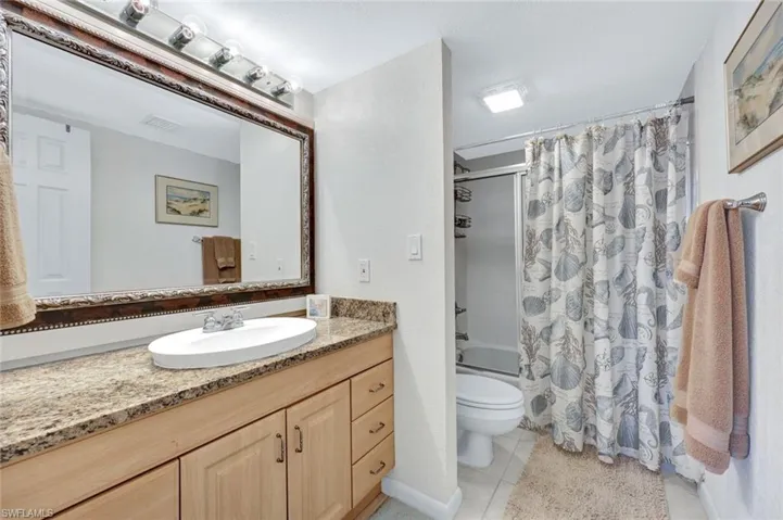 Full bathroom with shower / tub combo with curtain, vanity, toilet, and tile patterned flooring