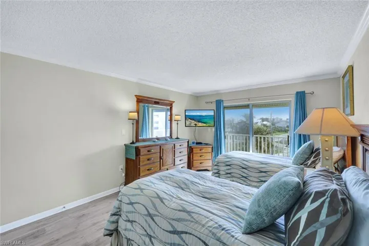 Bedroom featuring crown molding, access to outside, a textured ceiling, and light wood-type flooring