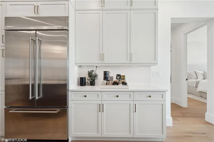 Bar with stainless steel built in refrigerator, white cabinets, and light hardwood / wood-style flooring