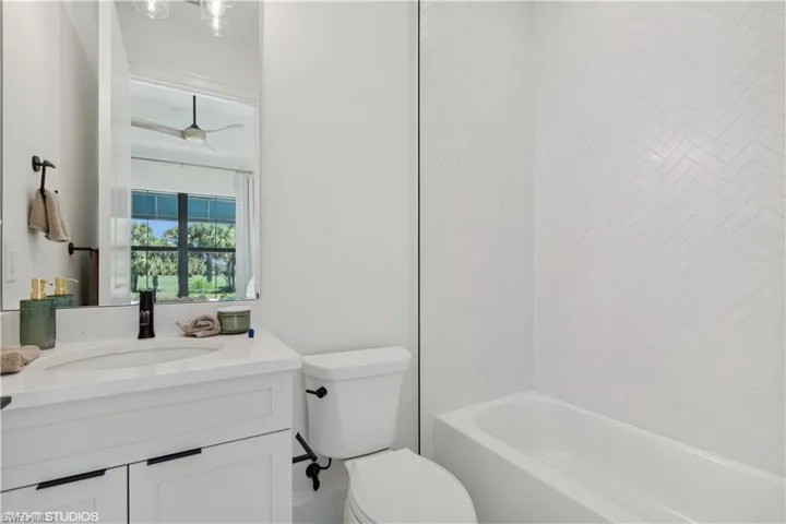 Full bathroom featuring shower / bathing tub combination, vanity, toilet, and ceiling fan