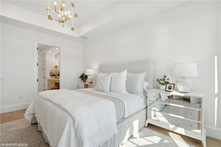 Bedroom featuring light hardwood / wood-style flooring, ensuite bath, and a notable chandelier
