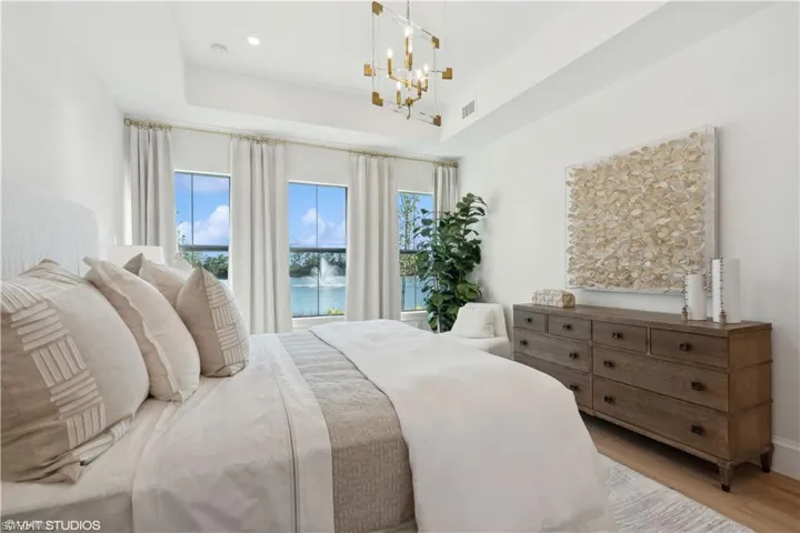 Bedroom with light hardwood / wood-style flooring, a chandelier, and a high ceiling