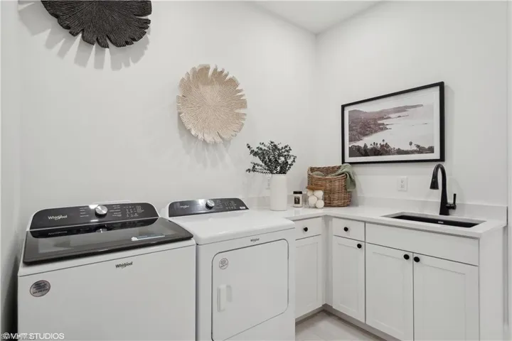 Laundry area featuring cabinets, washing machine and dryer, and sink