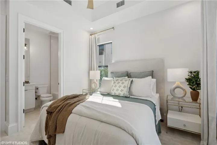 Carpeted bedroom featuring ensuite bath and ceiling fan