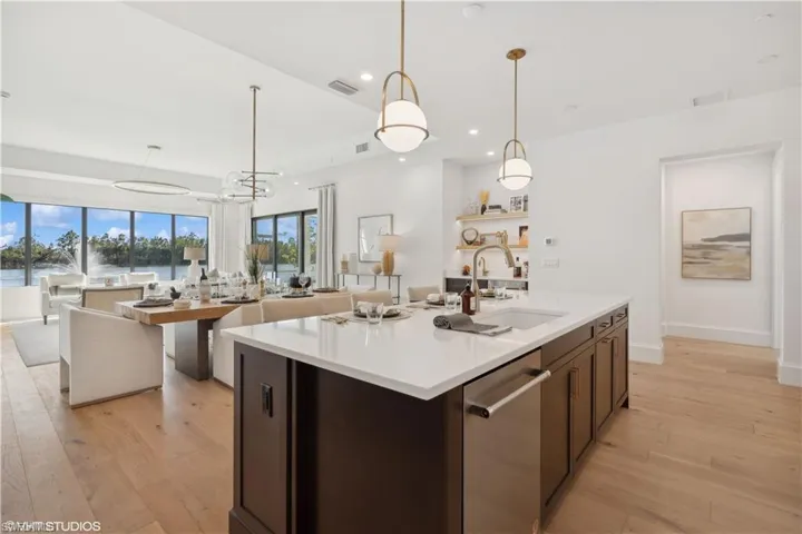 Kitchen featuring pendant lighting, sink, light wood-type flooring, an island with sink, and a chandelier