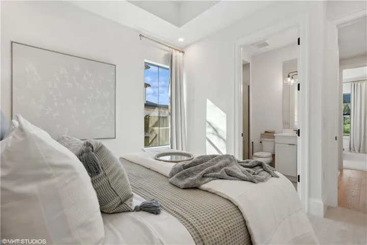 Bedroom with multiple windows, ensuite bathroom, and light hardwood / wood-style floors