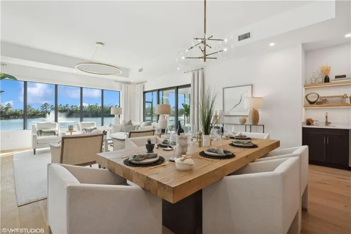 Dining space with a water view, light wood-type flooring, sink, and an inviting chandelier