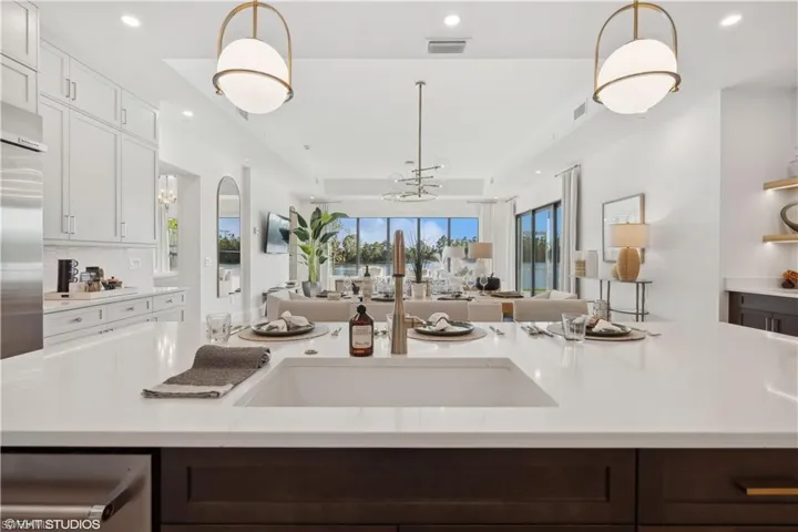 Kitchen with white cabinets, a healthy amount of sunlight, and hanging light fixtures