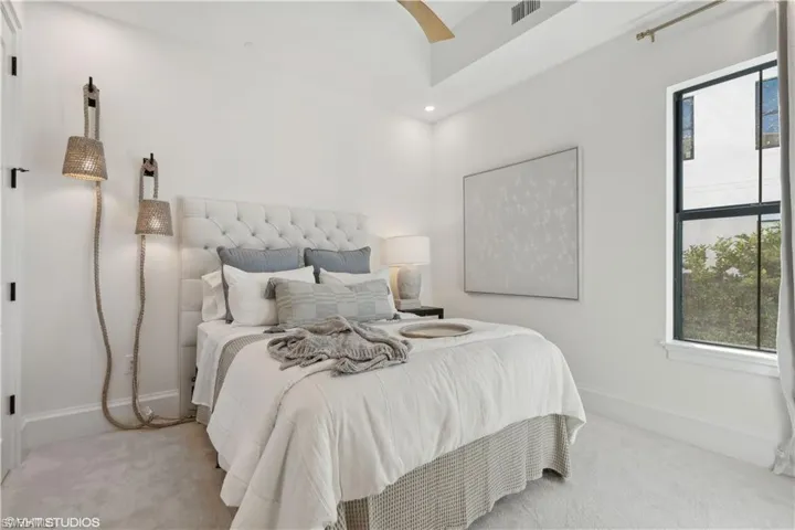 Carpeted bedroom featuring ceiling fan and multiple windows
