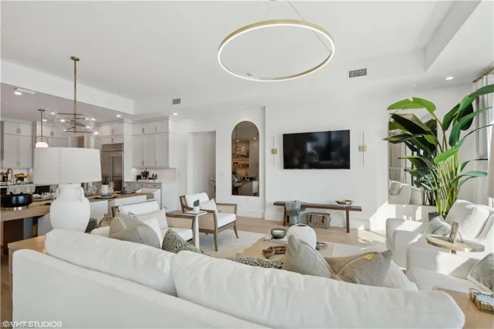Living room with a notable chandelier, a raised ceiling, and light wood-type flooring