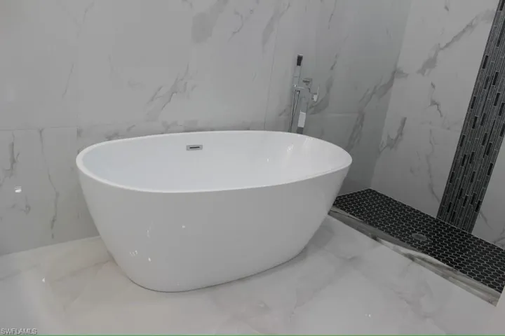 Bathroom with stone wall, marble finish floor, and a soaking tub
