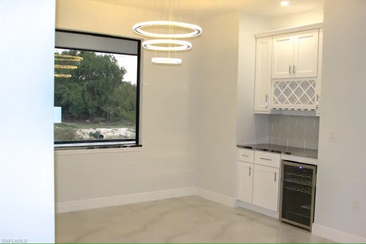 Kitchen area featuring a dry bar, plenty of natural light, backsplash, and wine cooler