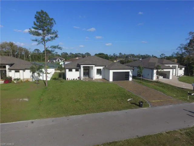 View of front facade featuring stucco siding, a garage, a front lawn, and decorative driveway