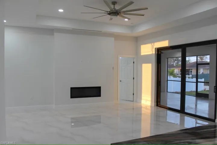 Living room featuring marble finish floor, baseboards, a fireplace, and a ceiling fan