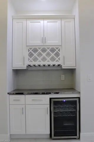Bar featuring decorative backsplash, baseboards, and beverage cooler