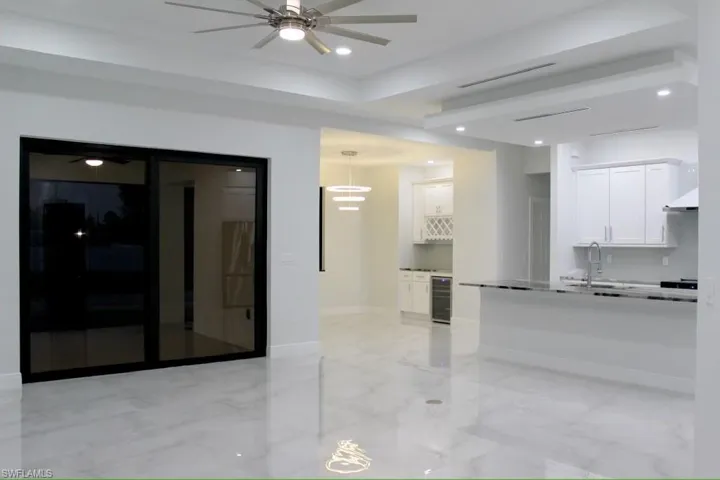 Kitchen featuring wine cooler, a sink, marble finish floor, white cabinets, and ceiling fan