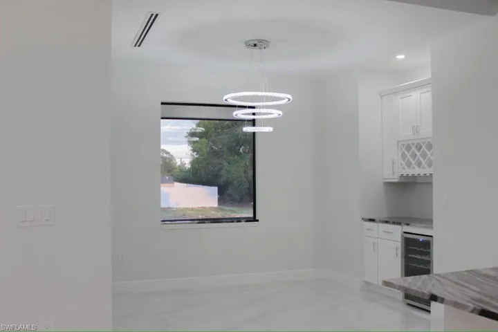 Kitchen featuring a notable chandelier, light stone countertops, beverage cooler, visible vents, and white cabinets