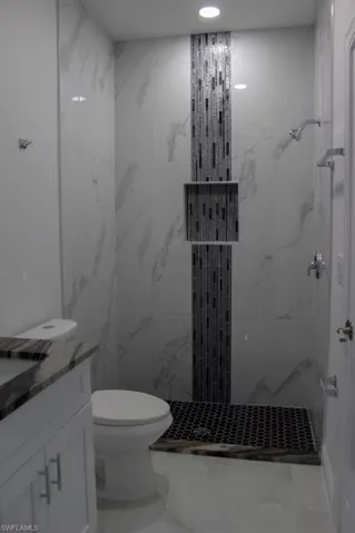Bathroom with marble finish floor, toilet, and a marble finish shower