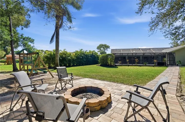 View of patio featuring a playground, a sunroom, a lanai, and a fire pit