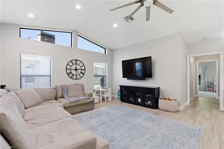 Living room featuring a ceiling fan, light wood-style floors, vaulted ceiling, and recessed lighting