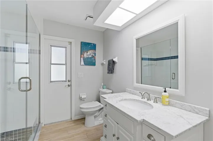 Bathroom featuring vanity, a shower stall, and light wood-style floors