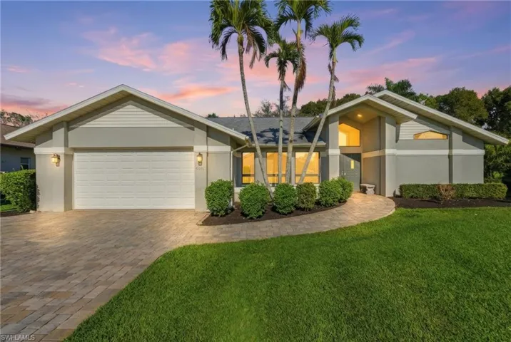 Mid-century modern home featuring stucco siding, a front lawn, a garage, and driveway