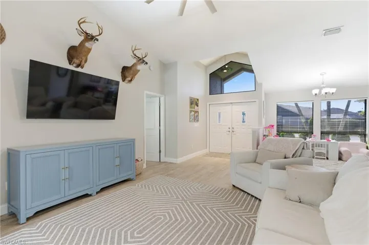 Living area with light wood finished floors, lofted ceiling, a chandelier, and ceiling fan