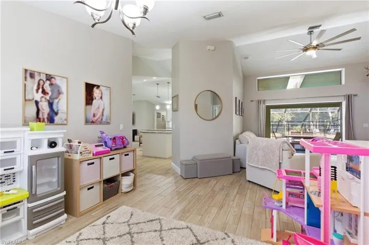 Playroom featuring lofted ceiling, light wood-style flooring, ceiling fan, and suspended lighting