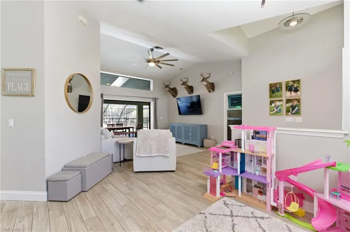 Game room featuring a ceiling fan, lofted ceiling, and light wood-type flooring
