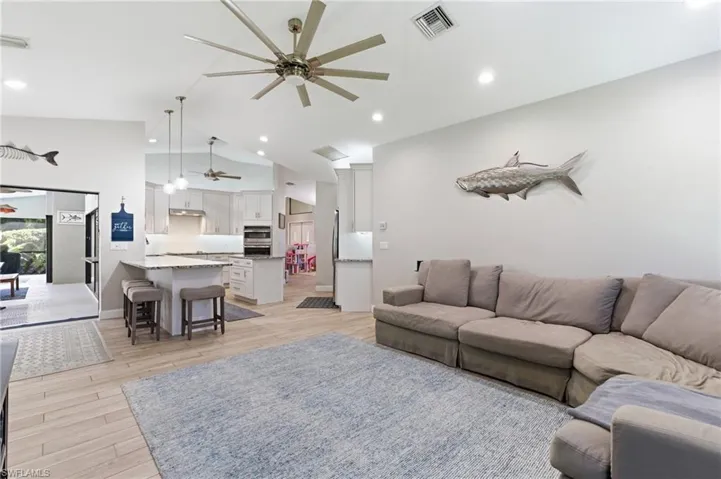 Living room with light wood-style flooring, a ceiling fan, lofted ceiling, and recessed lighting