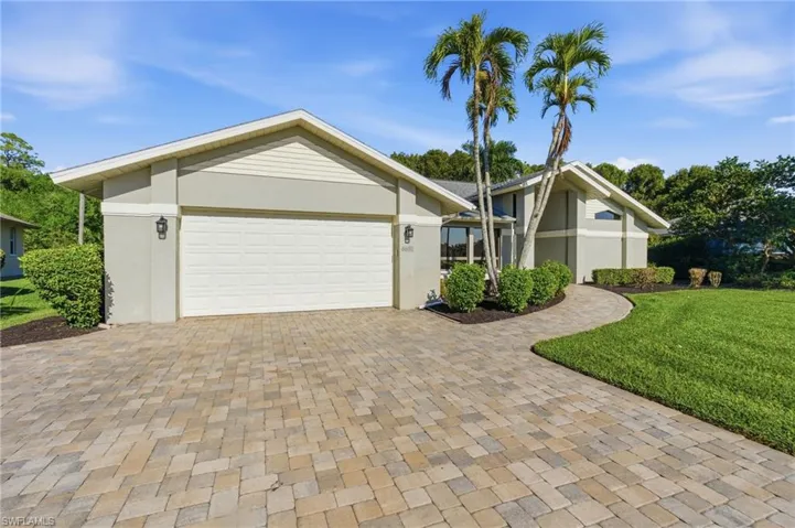 Mid-century inspired home with a front yard, decorative driveway, a garage, and stucco siding