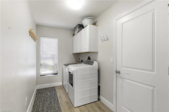 Laundry room with cabinet space, washer and dryer, and light wood-style flooring