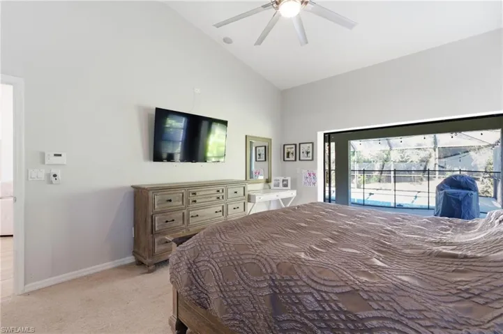Bedroom featuring lofted ceiling, access to exterior, light carpet, and a ceiling fan