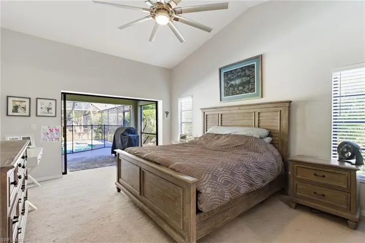 Bedroom featuring lofted ceiling, access to exterior, light colored carpet, a sunroom, and a ceiling fan
