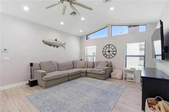 Living area featuring a ceiling fan, light wood-style flooring, lofted ceiling, and recessed lighting